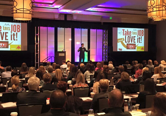 Dr. Mark on stage at a conference with purple lights in the background speaking to audience